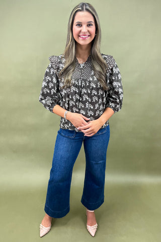 Brown floral smocked blouse with ruffle shoulders and balloon sleeves paired with wide-leg denim jeans for a chic fall outfit