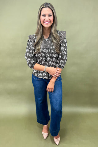 Brown floral smocked blouse with ruffle shoulders and balloon sleeves paired with wide-leg denim jeans for a chic fall outfit