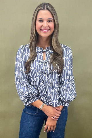 Woman wearing a patterned blouse and jeans against a green background