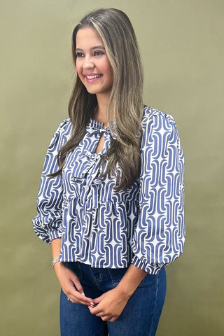Woman wearing a blue and white patterned blouse against a beige background