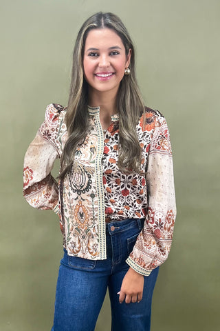 Woman wearing a patterned blouse and jeans against a green background