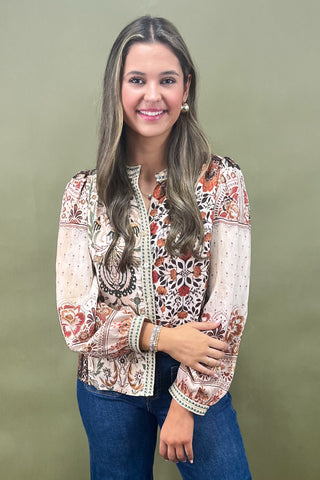 Woman wearing a patterned blouse with long sleeves against a green background