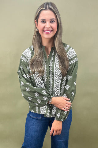 Woman wearing a green patterned blouse against a beige background