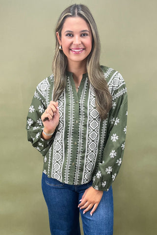 Woman wearing a green patterned blouse against a beige background