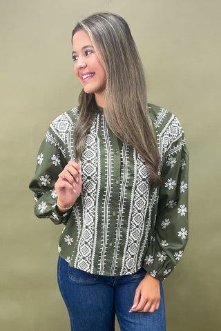 Woman wearing a green patterned blouse against a beige background