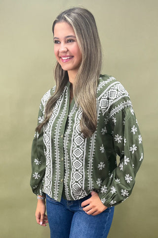 Woman wearing a green patterned blouse against a beige background