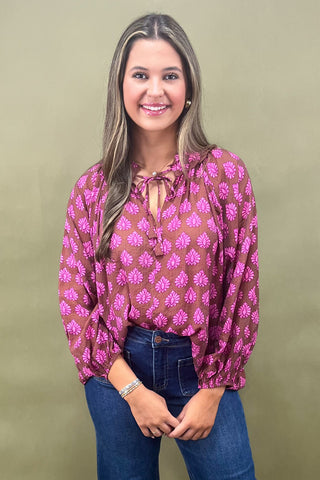Woman wearing a pink floral blouse and blue jeans against a green background