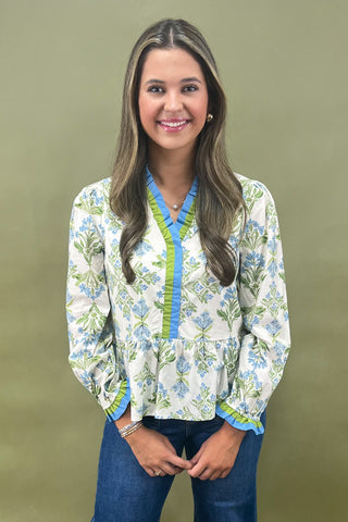 Woman wearing a floral blouse with blue accents against a green background