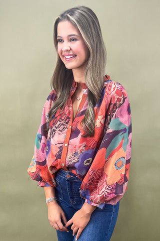 Woman wearing a colorful floral blouse against a plain background