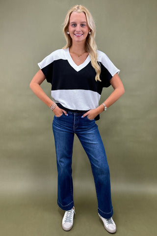 Woman wearing a black and white striped shirt and blue jeans on a green background