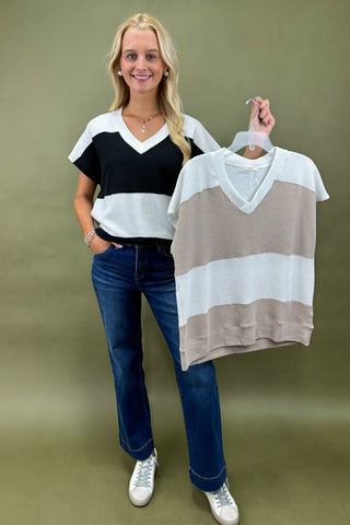 Woman holding a hanger with a striped shirt against a plain background