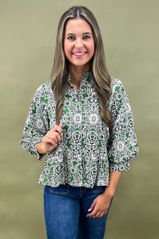 Woman wearing a green and white patterned blouse against a beige background