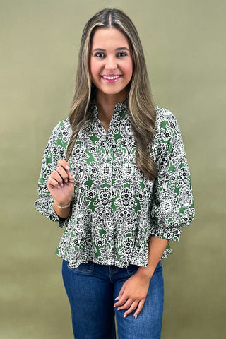 Woman wearing a green and white patterned blouse against a beige background
