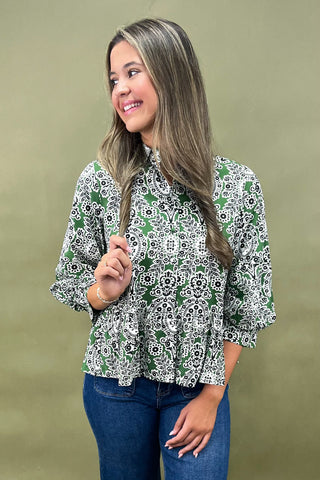 Woman wearing a green and white patterned blouse against a beige background