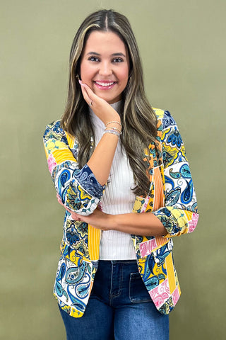 Woman wearing a colorful patterned jacket against a green background