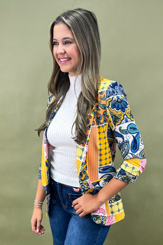 Woman wearing a colorful patterned jacket against a green background