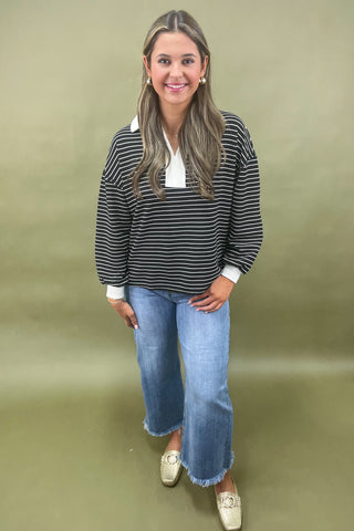 Woman wearing a striped sweater and jeans against a plain background