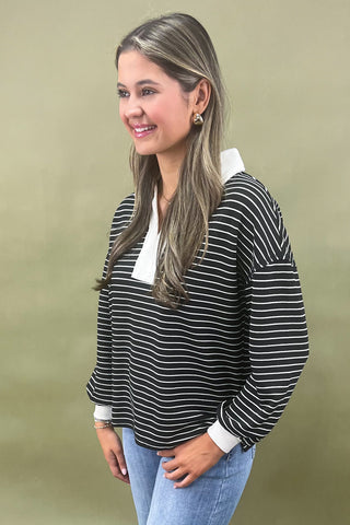 Woman wearing a black and white striped sweater with a plain background