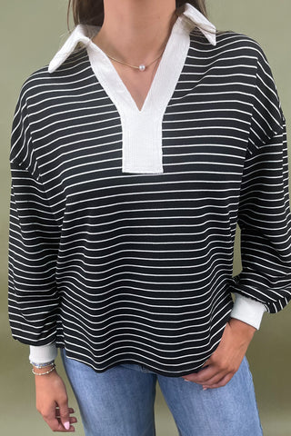 Black and white striped shirt with a white collar worn by a person against a green background