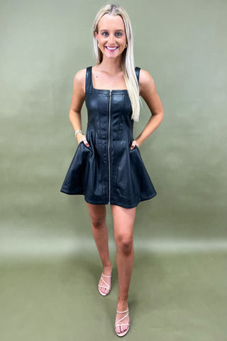 Woman wearing a black leather dress against a green background