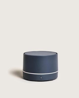Navy blue cylindrical speaker on a light gray background