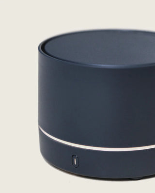 Dark blue cylindrical device with a white accent on a light gray background