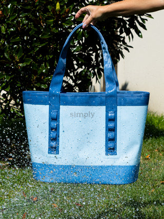 Blue and white tote bag with 'simply' branding being held outdoors.