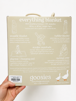 A hand holds a beige cardboard box labeled 'everything blanket' by Goosies. 