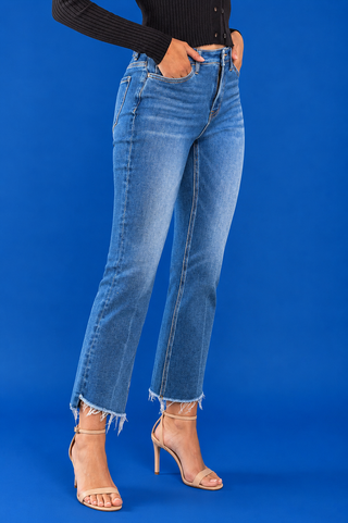 A model wearing medium-wash blue cropped flare jeans with a raw frayed hem