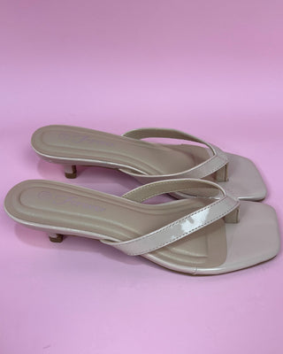Pair of beige sandals on a pink background