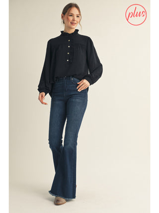 Woman wearing a black blouse and blue jeans on a beige background