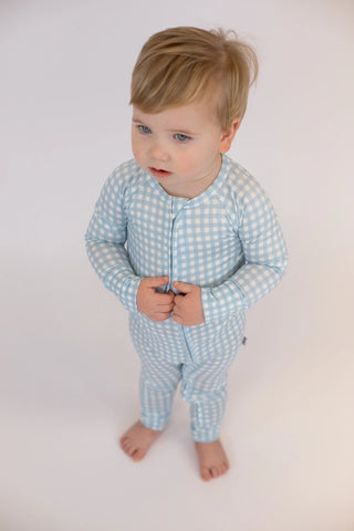 Child wearing a blue checkered outfit on a plain background