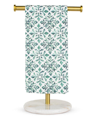 Decorative towel with a green and white pattern on a gold towel rack.