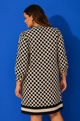 Woman wearing a polka dot dress against a blue background