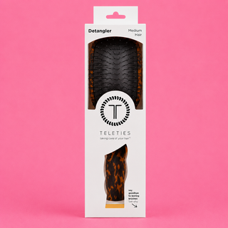 Teleties detangler brush packaging on a pink background