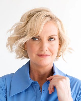 Woman with blonde hair wearing a blue shirt against a white background