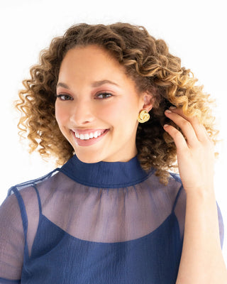 Woman with curly hair wearing a blue top against a white background