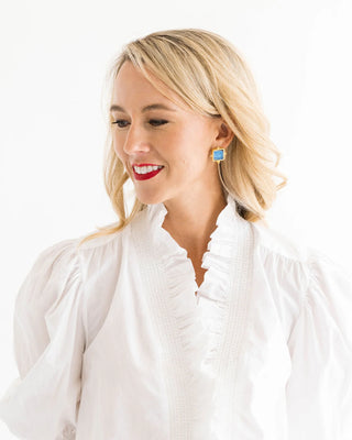 Woman wearing a white blouse with ruffled details on a white background