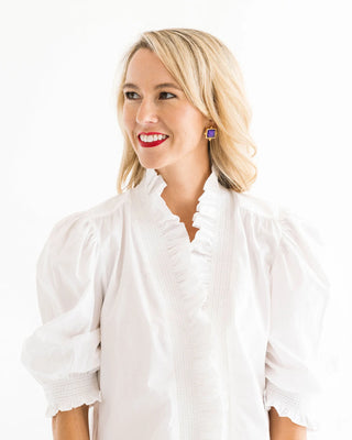 Woman wearing a white blouse with ruffled details on a white background