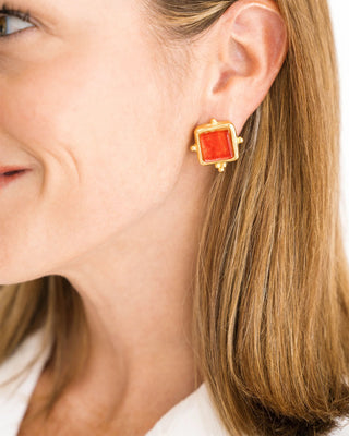 Close-up of a woman wearing a gold earring with a red stone.