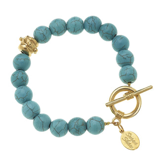 Turquoise beaded bracelet with gold clasp and tag on a white background