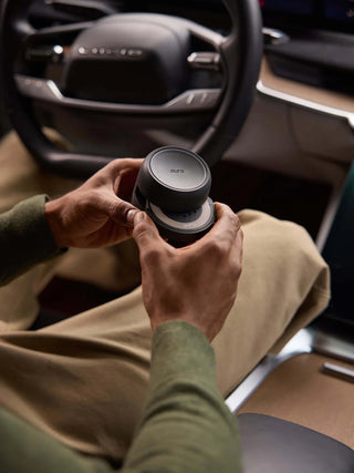 Person holding a black coffee cup with a lid inside a car.