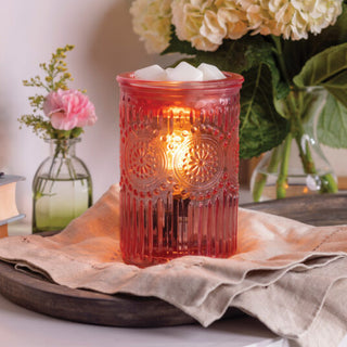 Decorative red lantern with a lit candle on a table with flowers and books in the background