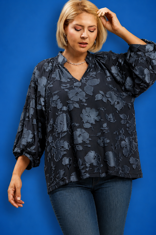 Woman wearing a dark floral blouse against a blue background