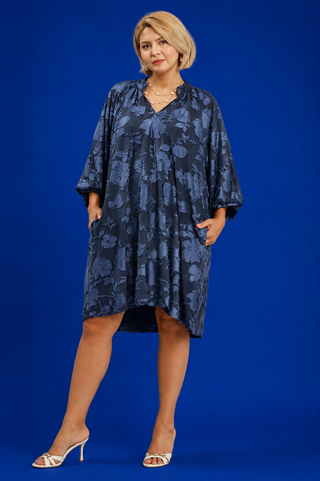 Woman wearing a blue patterned dress against a blue background