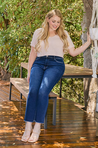 Woman sitting on a wooden bench outdoors with trees in the background