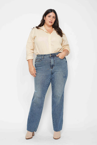 Woman wearing a beige blouse and blue jeans against a white background