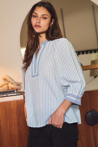 Woman wearing a blue and white striped shirt in an indoor setting