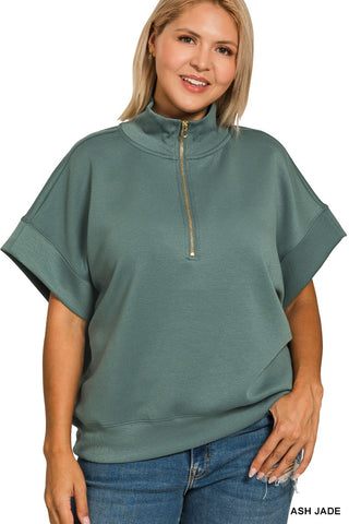 Woman wearing a green poncho with a gold zipper on a white background