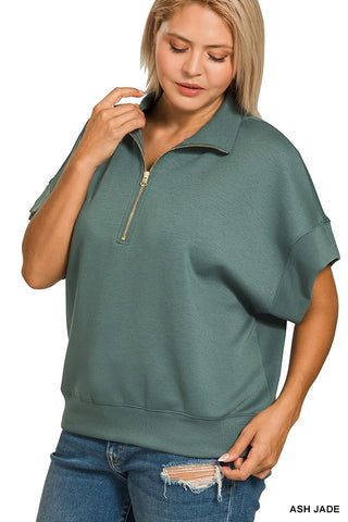 Woman wearing a green zip-up top and blue jeans on a white background